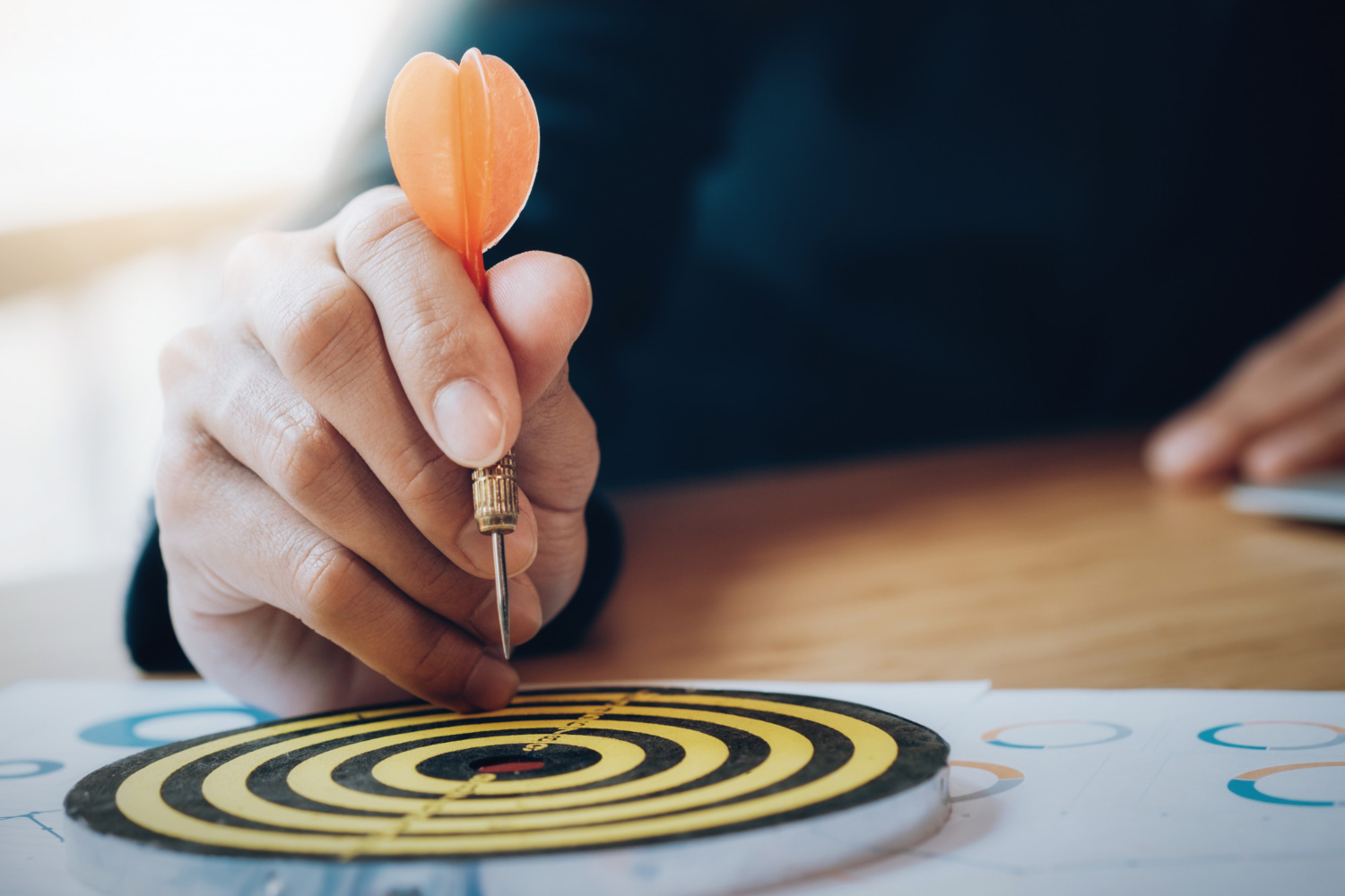 A hand placing a dart precisely on a target, representing mission focus